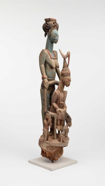 Wooden sculpture of seated king surrounded by family.
